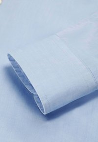 Lichtblauwe katoenenshirt mouw, met een gladde textuur en een dubbel gestikte manchet met een lichte kromming.