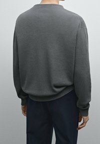 Dunkelgrauer, gerippter langärmeliger Pullover mit rundem Halsauschnitt und lässiger Passform, ausgestattet mit seitlichen Nähten und leicht herabgesetzten Schultern.