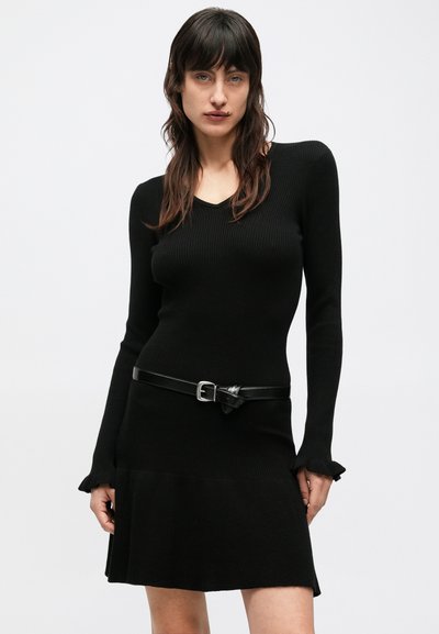 Čierne rebrované šaty s dlhými rukávmi a výstrihom do tvaru písmena V, zvýraznené úzkym čiernym opaskom v páse. Riasené lemovanie rukávov.