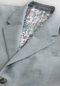 Hellgrauer Blazer mit dezentem Karomuster, mit floral bedrucktem Futter in Pastellfarben, mit Reverskragen und Knopfdetail.
