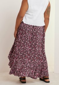 Blommig maxikjol i svart med rosa och vita blommor, lagerdesign, lättviktig tyg, avslutad fåll. Bärs med en vit, scalloped crop top.