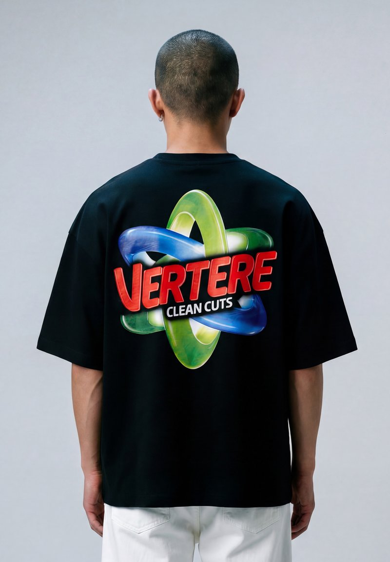 Persona con capelli corti che indossa una maglietta nera con anelli intrecciati colorati e testo rosso sul retro che dice "VERTERE CLEAN CUTS".