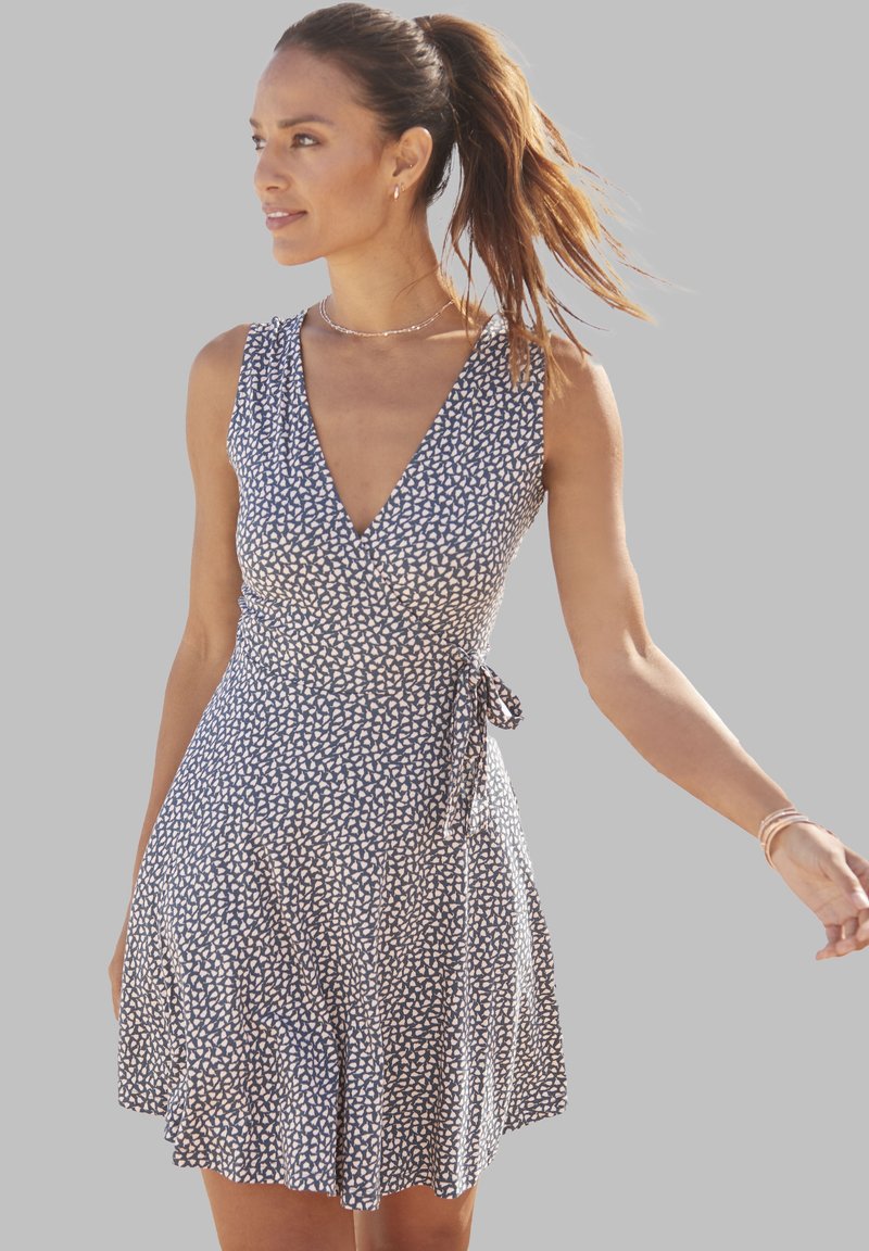 Ärmelloses blaues Kleid mit einem weißen Blättermuster, V-Ausschnitt, taillierter Taille und ausgestelltem Rock. Mit einem Bindeband in der Taille.