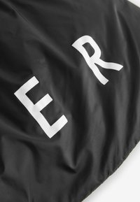 Sort stof med en glat tekstur, der har store hvide bogstaver "E," "R," og "R." Materialet er letvægtigt og lidt crimpe.