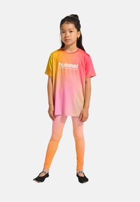 Hummel Performance t-shirt med en gradation från gult till rosa, i kombination med matchande ombre leggings i mjukt material. Svarta skor med randiga accenter.
