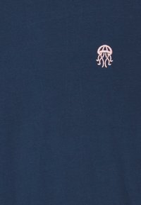 Marineblå bomulds T-shirt med en lille pink broderet vandmand på den øverste venstre bryst. Glat tekstur med en klassisk pasform.