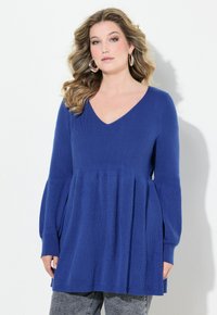 Blå stickad tröja med V-ringning, långa puffärmar och en utfälld nederkant. Mjuk textur med ett subtilt ribbat mönster.