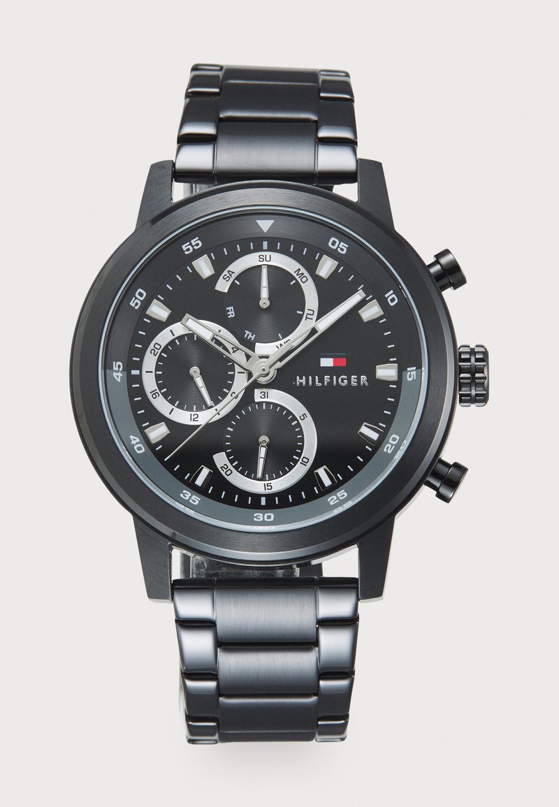 Montre en acier inoxydable noir avec trois sous-compteurs, accents argentés et un cadran noir. Présente une finition brossée et une couronne proéminente sur le côté.
