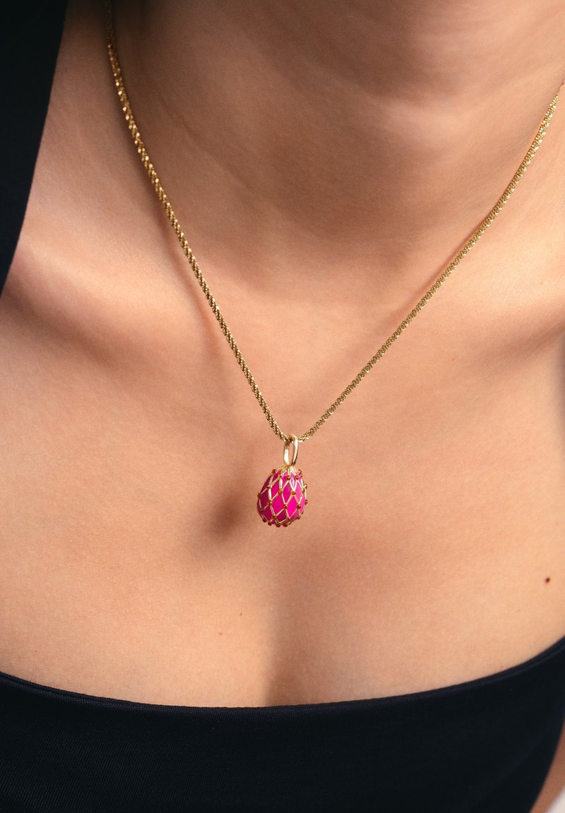Collier en or avec une fine chaîne torsadée mettant en valeur un pendentif rose en forme d'œuf orné d'un motif en treillis doré.