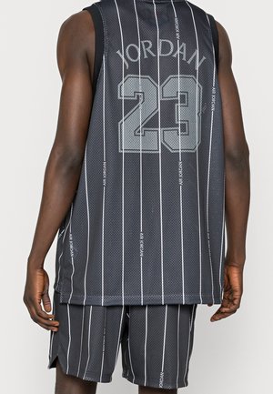 Homme portant un maillot et un short de basket Air Jordan noir rayé, affichant le texte « Jordan 23 » et le numéro au dos du maillot.