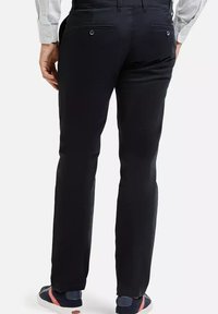 Czarne, proste spodnie wykonane z gładkiego materiału z dwiema tylnymi kieszeniami. Połączone z casualowymi butami w niebiesko-białych kolorach.