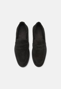 Mocassins en daim noir avec un design cousu, comportant une bande décorative sur le devant et un bout arrondi. Texture lisse et style à enfiler.