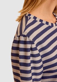 Sweter w niebiesko-srebrne paski o miękkiej strukturze. Posiada bufiaste rękawy oraz okrągły dekolt. Poziome paski na całej powierzchni.