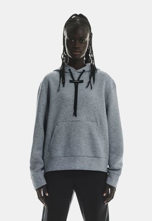 Sweat à capuche gris avec une grande poche avant, cordon de serrage à la capuche et accents noirs. Présente une coupe décontractée et une texture douce.