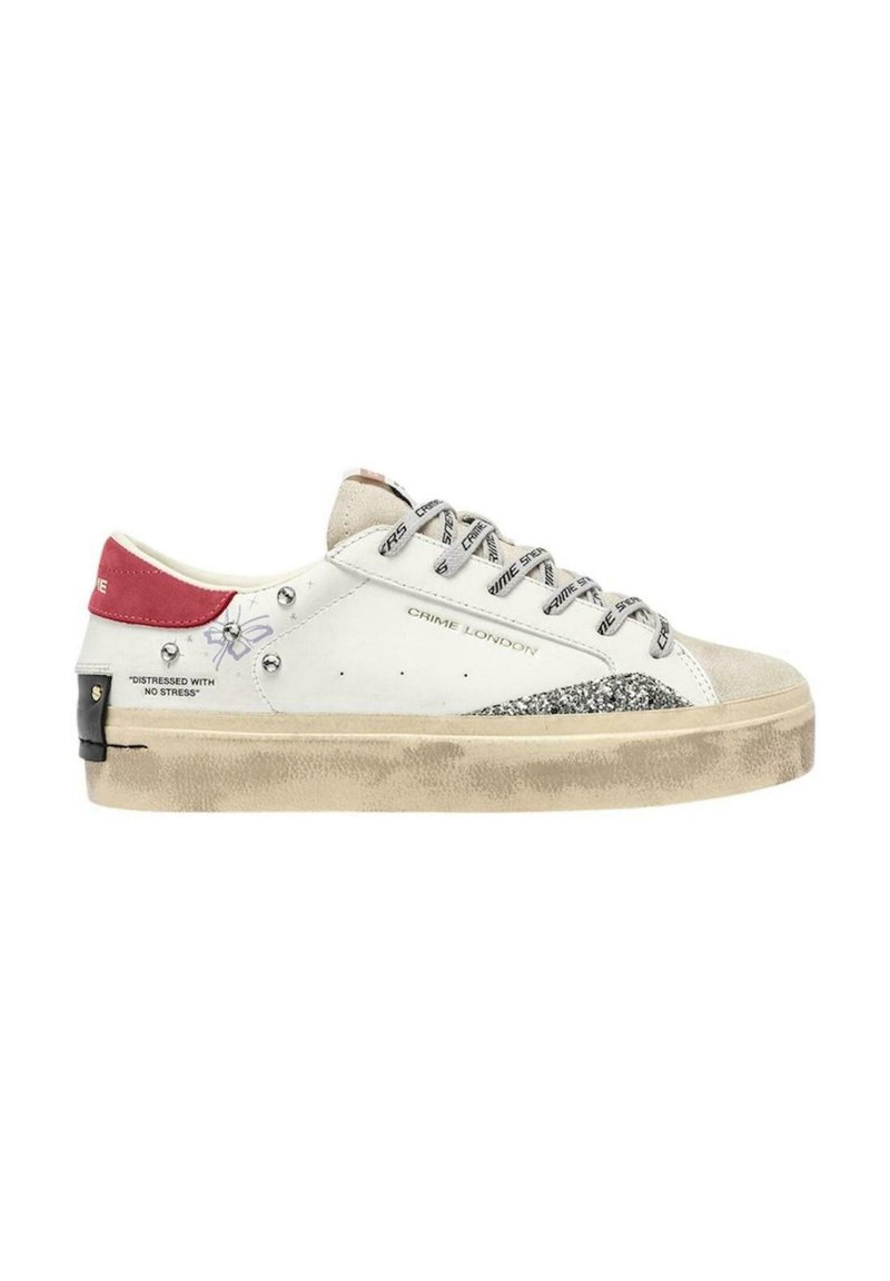 Sneaker bianco con accenti beige e glitter, hardware nero e lacci con logo. Presenta un look usurato e una linguetta sul tallone rossa.