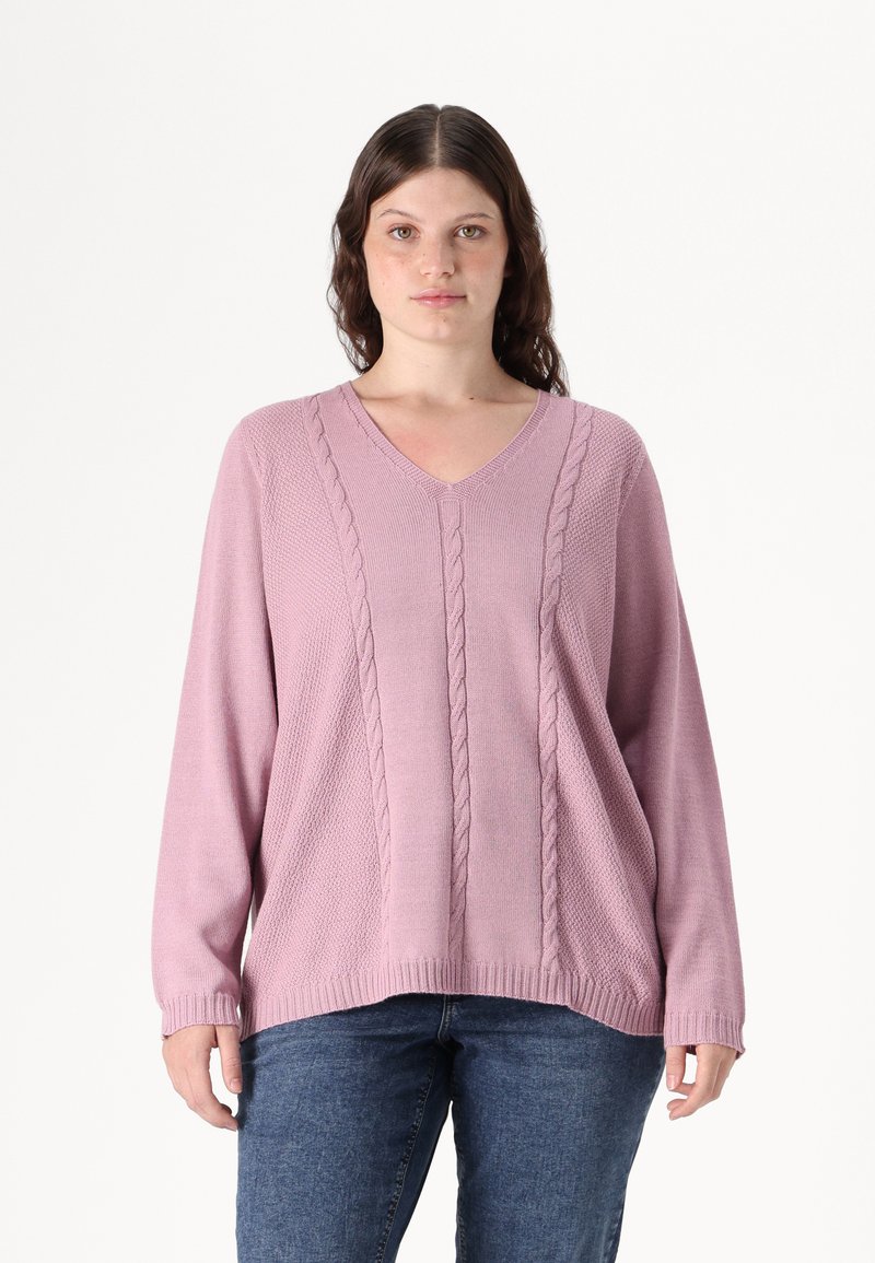 Ροζ πλεκτή ζακέτα με V-λαιμό, που διαθέτει λεπτομέρειες από καλσόν και μακριά μανίκια, συνδυασμένη με μπλε τζιν παντελόνι. Μαλακό, υφασμάτινο υλικό.