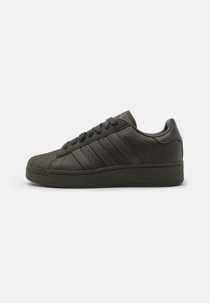 Schwarzer Adidas Superstar Sneaker mit Shell-Toe, drei Streifen an der Seite und passenden schwarzen Schnürsenkeln, in der Seitenansicht gezeigt.