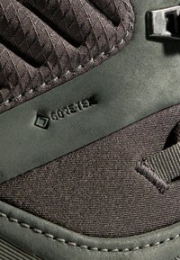 Scarpa da trekking grigio scuro con tomaia in tessuto testurizzato, aree di accento lisce e un'etichetta "GORE-TEX" impressa di lato.