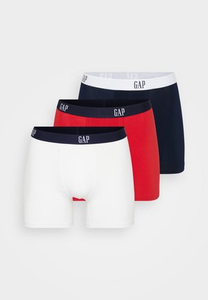 Trois paires de boxers pour hommes en blanc, rouge et bleu marine. Chacune présente une ceinture élastique avec le logo "GAP". Tissu en coton doux, coupe classique.