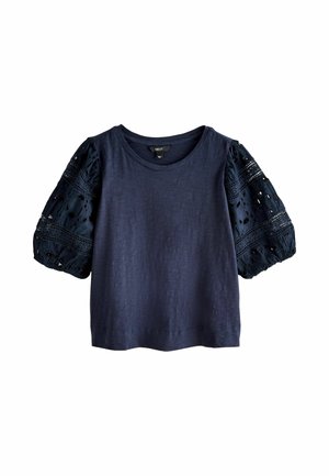 Granatowy krótki top z okrągłym dekoltem i bufkowatymi rękawami z koronkowym wzorem oraz wycięciami.