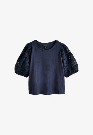 Námořnicky modrý top s krátkými rukávy, kulatým výstřihem a nadýchanými rukávy s krajkovým vzorem a výřezy.