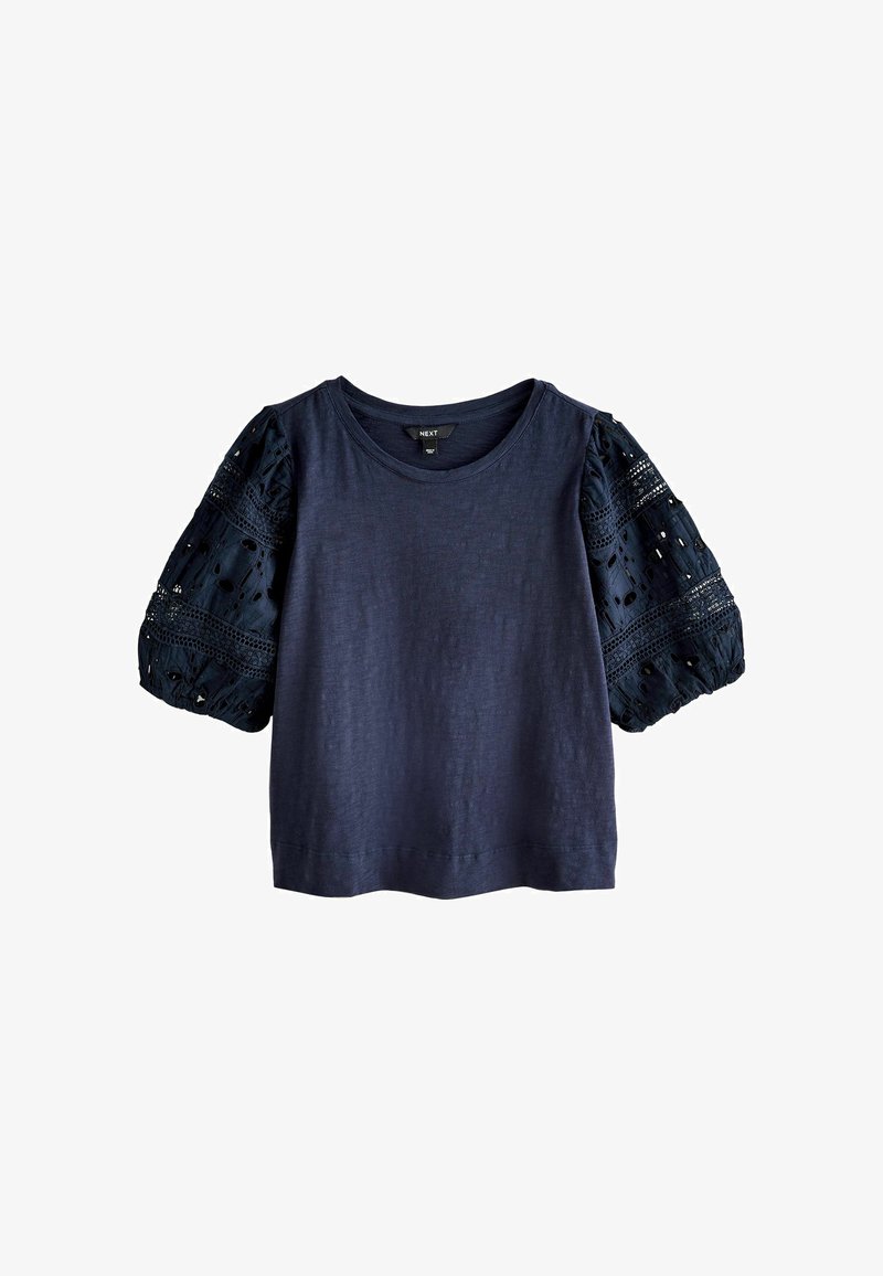 Haut bleu marine à manches courtes avec encolure ronde et manches bouffantes à motif en dentelle comportant des détails découpés.
