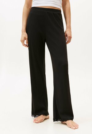 Zwarte ribbroek met een wijdbenig ontwerp en kanten trim aan de onderkant. Heeft een elastische tailleband voor comfort.