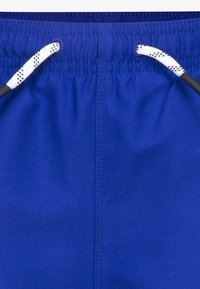 Blå badeshorts med elastisk midje, med en hvit snor med sorte detaljer, glatt tekstur og kontrastfargede sømmer.