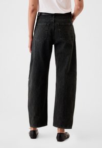 Musta leveälahkeiset farkut, valmistettu denimistä, joissa on korkeavyötärö, kaksi takataskua ja suora istuvuus nilkkaan saakka.