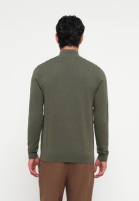Olive green knitted sweater with a high collar, long sleeves, and ribbed cuffs, made from a soft fabric. Minimalist design without patterns.