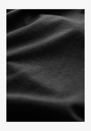 Tissu en coton noir avec une texture lisse, mettant en valeur des plis doux et un léger éclat, indiquant une grande flexibilité et une capacité à draper.