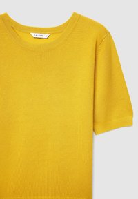 Yellow knit short-sleeve T-shirt with a round neckline and ribbed texture. Tag visible with brand name "Calliope" and size "S."