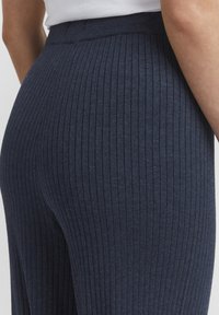 Navy ribbed leggings with a high waistband, featuring vertical texture and a soft material. Close-up view emphasizes the stitch detail.