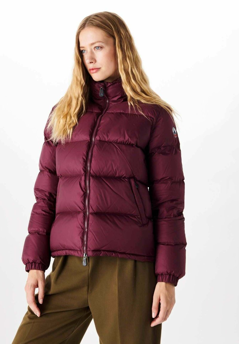 Giacca puffer borgogna con colletto alto, chiusura con zip e polsini elasticizzati. Presenta motivi a quadri orizzontali e tasche laterali.