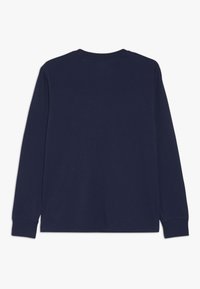 Långärmad skjorta i marinblått, tillverkad av mjukt material. Har rundad halsringning och en enkel, rak skärning utan synliga logotyper.