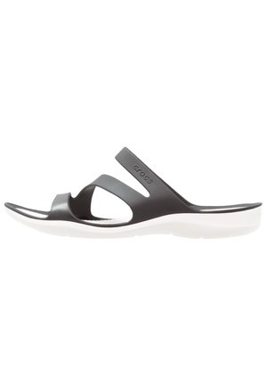 Sandale slide Crocs noire avec deux brides et semelle blanche, vue de côté sur fond blanc.