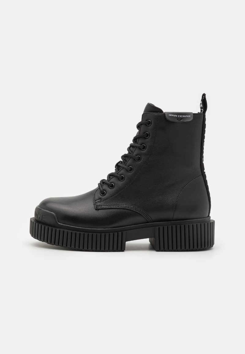 Bottines en cuir noir, avec une semelle épaisse et rainurée, des lacets à l'avant et une languette à l'arrière ornée d'un logo.