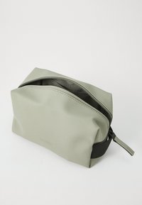Green waterproof toiletry bag with a smooth texture, rectangular shape, top zipper closure, and subtle branding on the front.