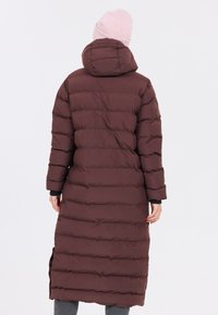 Brun pufferjakke med et langt, polstret design, hætte og sideslids. Glat tekstur med vandrette quiltede segmenter og lange ærmer.