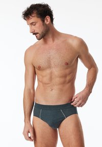 Herrenunterhosen aus dunkelgrauem Stoff mit glatter Textur. Sie verfügen über einen breiten elastischen Bund und kontrastierende weiße Nähte.