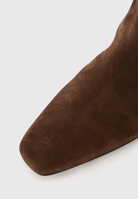 Brown suede ankle boot with a pointed toe and smooth texture. Features a seamless design without visible hardware or accents.