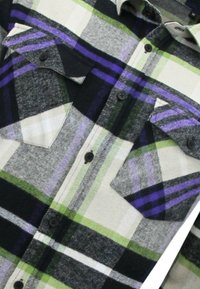 Geruite flanellen overhemd in groen, zwart, paars en grijs. Het heeft een gekraagde halslijn en twee borstzakken met knoopsluitingen.