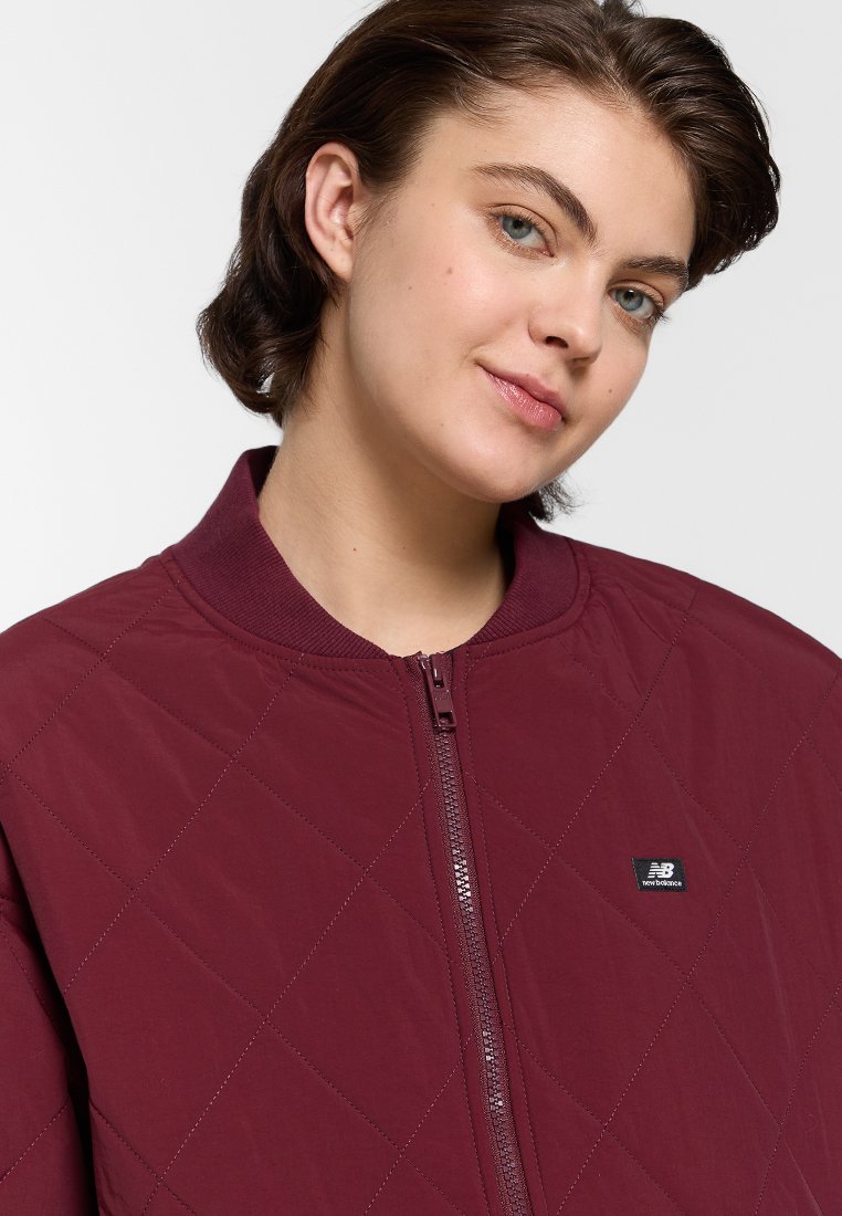 Chaqueta bomber acolchada en color marrón con cierre de cremallera y cuello redondo. Incluye un pequeño logo en el lado izquierdo.