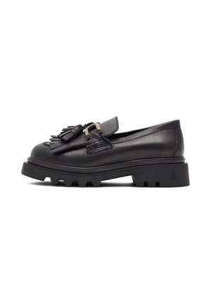 Mocasines de cuero negro con una suela de goma gruesa, flecos decorativos en la parte delantera y un detalle de hebilla. Textura suave y forma amplia.