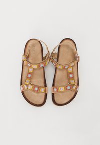 Sandales plates marron avec une sangle décorative présentant des motifs carrés brodés multicolores. Matériau doux ressemblant à du daim et design ouvert.