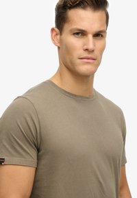 Olijfgroene t-shirt met korte mouwen in een soepele katoenmix; ronde halslijn; voorzien van een klein logotag op de linker mouw.