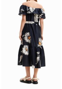 Laivansinis off-the-shoulder mekko, jossa on kukkakuosi, röyhelökaulus ja kerroksellinen hame. Yhdistetty litteisiin sandaaleihin, joissa on hihnat ja musta pohja.