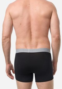 Schwarze Baumwollboxershorts mit einem grauen elastischen Bund, von hinten betrachtet. Bietet eine glatte Textur und eine figurbetonte Passform.