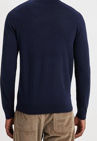 Mörkblå stickad tröja med långa ärmar och rund halsringning, med en slät yta och figursydd design, utan synliga mönster eller accenter.