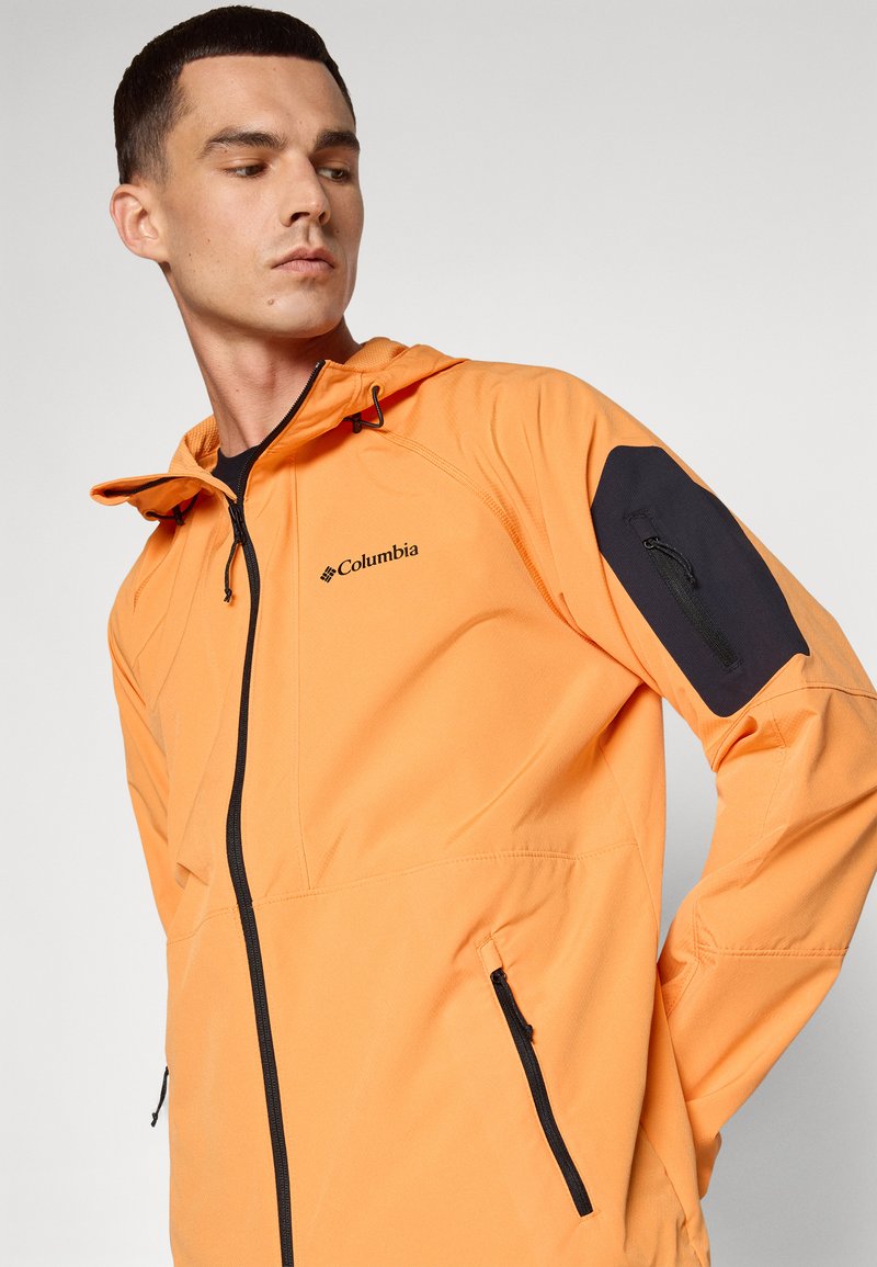 Kurtka z kapturem w intensywnym pomarańczowym kolorze, z zamykanymi na zamek kieszeniami i czarnymi akcentami. Wykonana z oddychającego materiału o eleganckim, sportowym kroju.